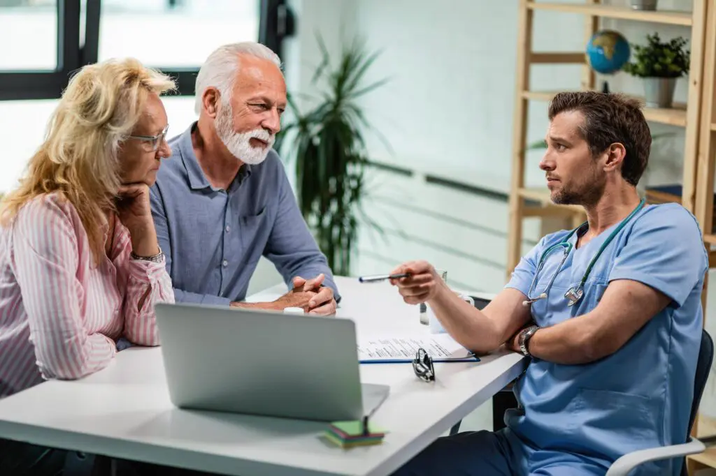 Doctor consulting with elderly couple at desk.